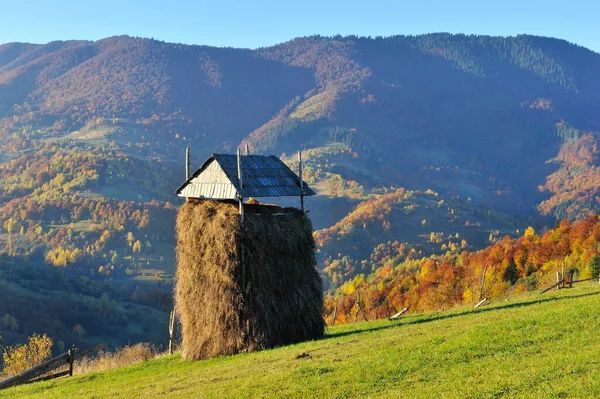 Beautiful autumn mountain landscape in the morning light. Haystack on the background of autumn slopes