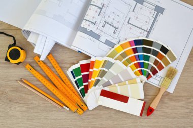 Architectural drawings with color guide, brushes, pencils, ruler on wooden background. Top view. Repair housing concept.