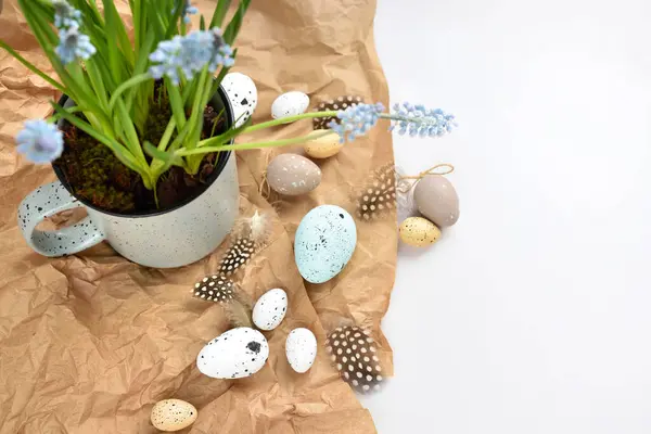 复活节彩蛋和淡蓝色麝香花在一个白色桌子上的杯子里 复活节宁静的生活 顶部视图 图库图片