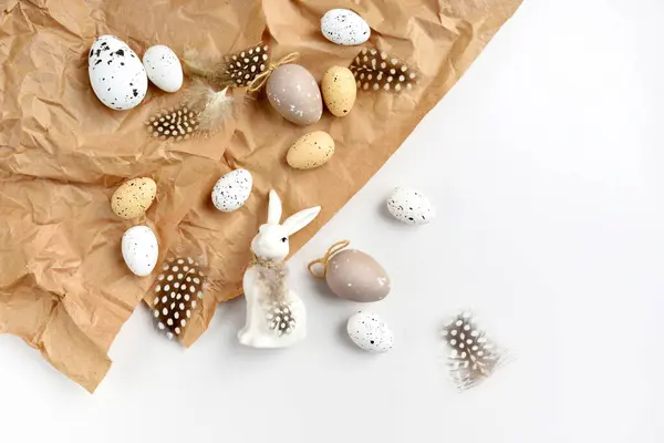 复活节的作文 白色的兔子 蛋和羽毛在褐色的牛皮纸背景上 白色的桌子上 顶部视图 适用于带有复制空间的东方贺卡 图库照片
