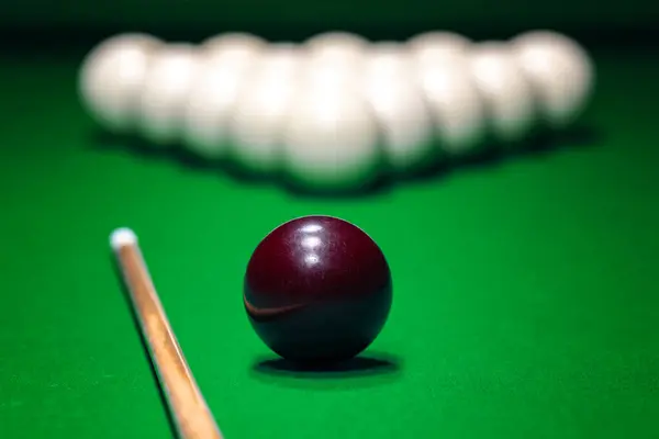 Red ball is displayed on the pool table against the background of other balls and cue