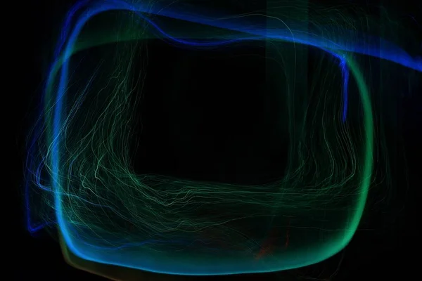 Karanlık arka planda soyut ışık resmi. Merkezdeki boşluğun etrafındaki renkli ışık çizgileri
