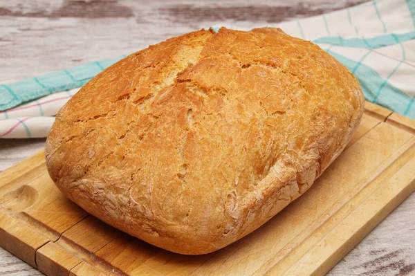 Yeni pişmiş bir somun ekmek kesim tahtasının üzerinde duruyor.