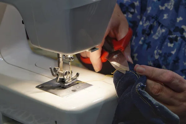 Kadın dikiş makinesinde dikiş dikiyor.