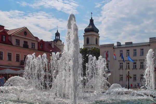 Polonya 'nın Plock kentindeki Eski Pazar Meydanı' nı çevreleyen binaların arka planında akan bir çeşme.