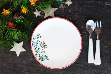 Yılbaşı sofrası. Parlak bir çelengi, yıldızları, yeni bir ağacı ve ahşap arka planda konileri olan bir Noel süsü. Üst görünüm