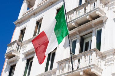 Balkonda beyaz bir eve İtalyan bayrağı sallıyor.