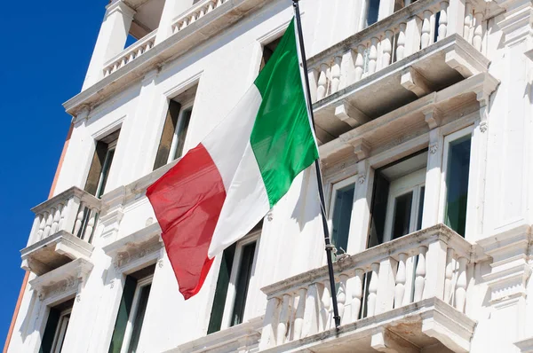 Balkonda beyaz bir eve İtalyan bayrağı sallıyor.