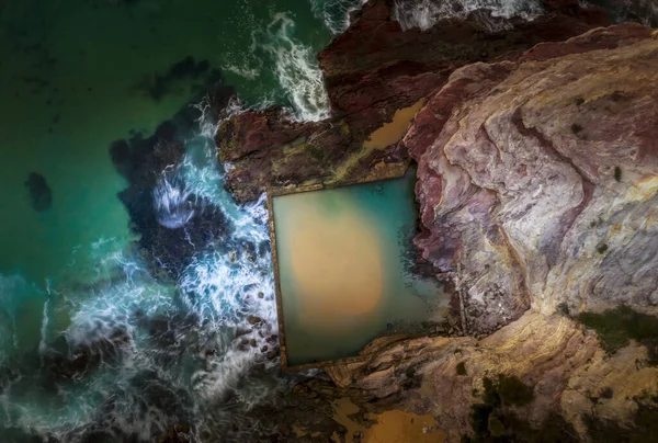 波はエデンの赤と黄色の崖に構築された海の岩のプールにオーバーフロー ストック画像