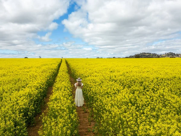 春天里 身穿长裙的女性站在开花结果的科诺拉农田里 — 图库照片