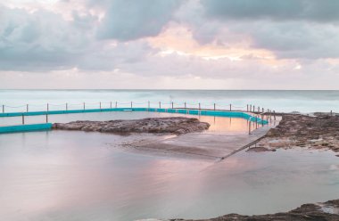 South Curl 'deki okyanus taşı havuzu. Havuzun turlar için bir bölümü, (uzak uç) ve düzensiz bir derinliği vardır. Doğal kayaların bir kısmı da havuzun bir kısmını oluşturur. Uzun süre maruz kalmak, rüzgarlı bir günde denizi ve havuzu sakinleştirir..