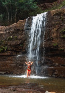 Serin bir şelalenin altında duran kadın suyun vücuduna düşmesine izin veriyor. 