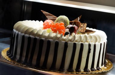  Close-up view of decorated cake in refrigerated display unit of a bakery shop                                