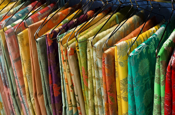  View of Indian woman traditional dress sarees in display, on hangers in a shop                                           