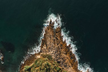 Deniz kıyısının aşağısındaki hava manzaralı büyük dalgalar kayalık bir uçuruma çarpıyor. Gün batımında güzel bir karanlık deniz yüzeyi. Deniz manzaralı inanılmaz bir deniz manzarası. Yüksek kaliteli drone fotoğrafı.