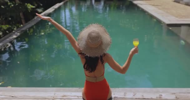 Una Mujer Traje Baño Sombrero Paja Sienta Fondo Piscina Disfrutando — Vídeo de stock