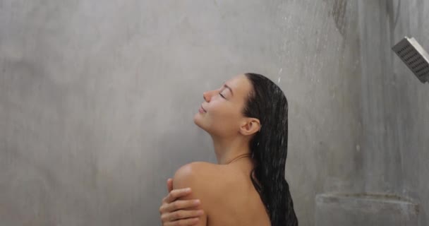 スローモーションでシャワーを浴びている若い大人の女性の閉鎖 美しい女の子のシャワーのバックビューでは リラックスした時間を楽しんで彼女の髪を洗う 滴と彼女の体に水の流れ 高品質 — ストック動画