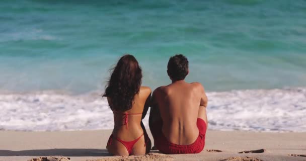 男人和女人坐在沙滩上的海边聊天 一个黑发白人女人和一个男人背对着摄像机坐在那里 看着海浪 浪漫的概念 — 图库视频影像