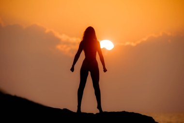 Silhouette of a mentally and physically strong woman standing on a mountaintop at sunrise. People, power, and strength concept. High-quality photo clipart