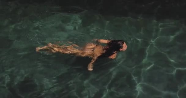 在空中俯瞰一个身材苗条的年轻性感女人穿着黑色比基尼在豪华热带度假胜地游泳池游泳 慢动作4K镜头 — 图库视频影像