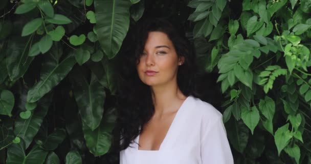 在异国情调的热带植物中 有着自然妆容和发型的时尚女孩的自然美肖像站在白色时尚的衣服中 高质量的4K慢镜头 — 图库视频影像