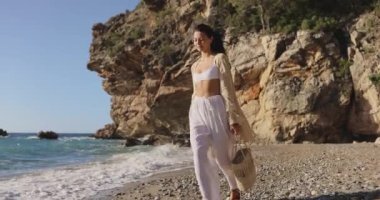 Çekici, romantik, çok kültürlü Asyalı, Kafkas plaj kadını modelleri moda yaz kıyafetleri giyip, sabah deniz tatilleri sırasında Rocky Beach 'te yürüyüş yapıyorlar. Yüksek kalite sinematik yavaş