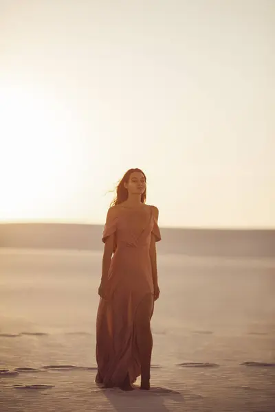 Romantic fashionable woman model in the desert in evening pink dress. Gorgeous slim girl outdoors. High quality photo