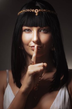 Tarihi gizem ve güzellik sırları. Kraliçe Kleopatra stüdyoda dudaklarında parmaklarıyla güzel bir kadın portresi yapıyor. İnanılmaz baştan çıkarıcı genç kadın mükemmel Mısır makyajıyla ve antik firavunla