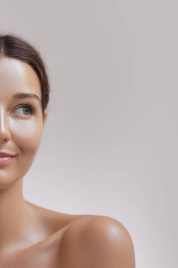 Cilt bakımının ve kozmetik konseptinin kaliteli fotoğrafı. Güzel yüzlü bir kadın, sağlıklı bir yüz portresi. Doğal makyajlı güzel mutlu Asyalı kız modeli parlayan hidratlı derinin tadını çıkarıyor.