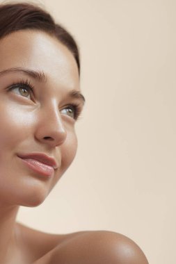 Cilt Bakımı Sağlıklı Cilt Bakımı, Doğal Makyaj. Bej arka planda çıplak omuzlu genç, mutlu kız modeli. Yüksek kaliteli güzellik ürünü veya tedavi kavramsal