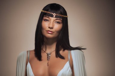 Kleopatra makyajlı muhteşem bir kadının fotoğrafı, şık saç kesimli, tarımcı altın arka planlı güzel bir kadının yakın plan portresi, şık altın kolye takan genç bir bayan, güzellik salonu. Yüksek