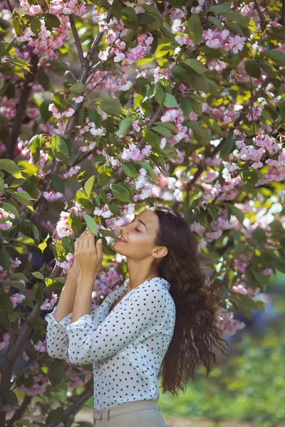 Bahar kızı suratı. Sakura Çiçekleri 'nin arka planında narin bir kadının portresi. Hanami kutlaması Sakura çiçek bahçesinde. Sakura parkında duran ve pembenin güzelliğinin tadını çıkaran şık bir kadın.