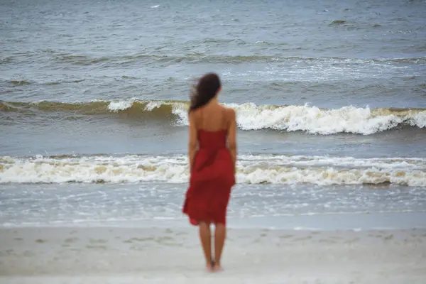 Жінка Червоній Сукні Стоїть Холодному Вітряному Пляжі Фокус Морі Ліцензійні Стокові Фото
