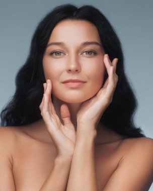 Çıplak omuzları ve pürüzsüz bir cildi olan sakin bir güzellik. Yumuşak mavi bir eğime karşı. Spa, rahatlama ve sağlıkla ilgili betimleme için ideal.. 