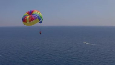 Parasailing. Bir teknenin arkasında paraşütle uçan aile manzarası. Sahilde ekstrem su sporu ve deniz eğlencesi