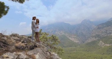 Türkiye 'nin Antalya kentinde manzaralı bir dağ manzarasında kucaklaşan romantik bir çiftin yavaş çekim görüntüleri. Seyahat blogları, romantik kaçamaklar ve doğa temalı içerik için mükemmel..