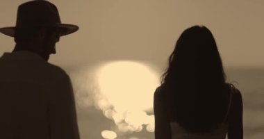 Bir çift, gün batımında okyanusun kenarında bir siluet gibi hassas bir anı paylaşıyor. Aşk, romantizm ve dinginlik temaları için mükemmel, reklamlar ve seyahat promosyonları için ideal.. 