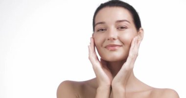 Genç, çok ırklı Asyalı, beyaz tenli, gülümseyen ve yüzüne nazikçe dokunan beyaz bir kadının yakın çekimi. Güzellik, cilt bakımı, sağlık için mükemmel.