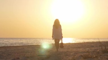 Gün batımında plajda elinde ukulele ile yürüyen boho tarzı bir kadının silueti. Yavaş çekim bir özgürlük ve dinginlik hissi yakalıyor. Seyahat, yaşam tarzı ve müzikle ilgili ideal