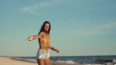 Güneşli bir plajda frizbi oynayan genç bir kadın, ağır çekimde yakalandı. Eğlence, özgürlük ve yaz aktiviteleri için ideal. Seyahat ve yaşam tarzı promosyonları için mükemmel bir görüntü.. 