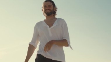 Gülümseyen adam, güneşli bir sahilde, günlük kıyafetlerle frizbi oynamaktan zevk alıyor. Boş zaman, eğlence ve açık hava aktiviteleri için mükemmel bir kavram. Yaşam tarzı ve seyahat için yüksek kaliteli görüntü ideal