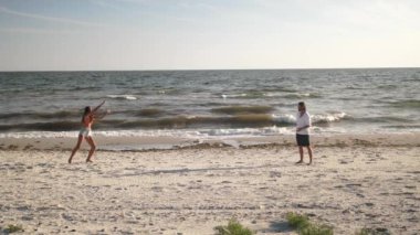 Güneşli bir sahilde frizbi oynayan çift yavaş çekimde yakalandı. Açık hava eğlencesi, eğlence ve yaz aktiviteleri için mükemmel bir kavram. Yaşam tarzı ve seyahat için yüksek kaliteli görüntü ideal
