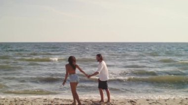 Neşeli çift birbirlerine doğru koşuyorlar güneşli bir sahilde sarılıp öpüşüyorlar, neşeli bir anda yakalanmışlar. Aşk, mutluluk ve yaz eğlencesi kavramları için mükemmel. Yüksek kalite sinematik yavaş
