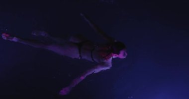 Sakin, genç bir kadın geceleri yüzme havuzunda dinleniyor, yukarıdan manzara seyrediyor. Yüksek kalite ağır çekim 4k görüntü. 