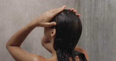 Bir kadın şehvetli bir duştan zevk alır, saçlarını hafif bir su akıntısı altında yıkar. Samimi ortam, rahatlama ve kendine bakmanın özünü yakalar. Güzellik ve refah için mükemmeldir..