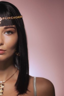 Zarafet ve güzelliğini vurgulayan Kleopatra 'dan esinlenilmiş altın bir başlık ve mücevher takan bir kadının çarpıcı bir yarı yüzü. Moda, kültür ve tarihsel temalar için mükemmel.