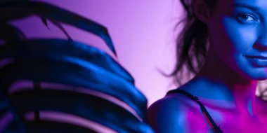 Gizemli yarım yüzlü kadın portresi, neon ışıkla aydınlatılmış, c palmiye yaprağı. Yaratıcı, editör ve moda projeleri, partiler ve gece hayatı için mükemmel, entrika ve modern