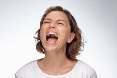 Güçlü ve agresif bir ifadeye sahip bir kadın beyaz bir arkaplanda tutkuyla bağırıyor, yoğunluk ve kararlılık temalarını aktarıyor. Promosyon içeriği, reklamlar ve...