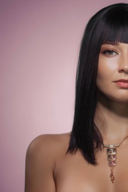 Zarif, siyah saçlı, zarif makyajlı ve pembe arka planda şık takılar takan zarif bir kadın portresi. Güzellik kampanyaları, moda yazıları ve lüks markalar için ideal.