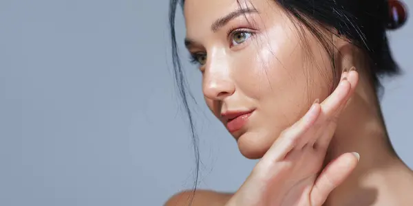 stock image Portrait of an elegant woman with hydrated skin and a graceful hand pose against a blue background. Perfect for beauty, skincare, and cosmetics advertisements and high-quality promotional materials.